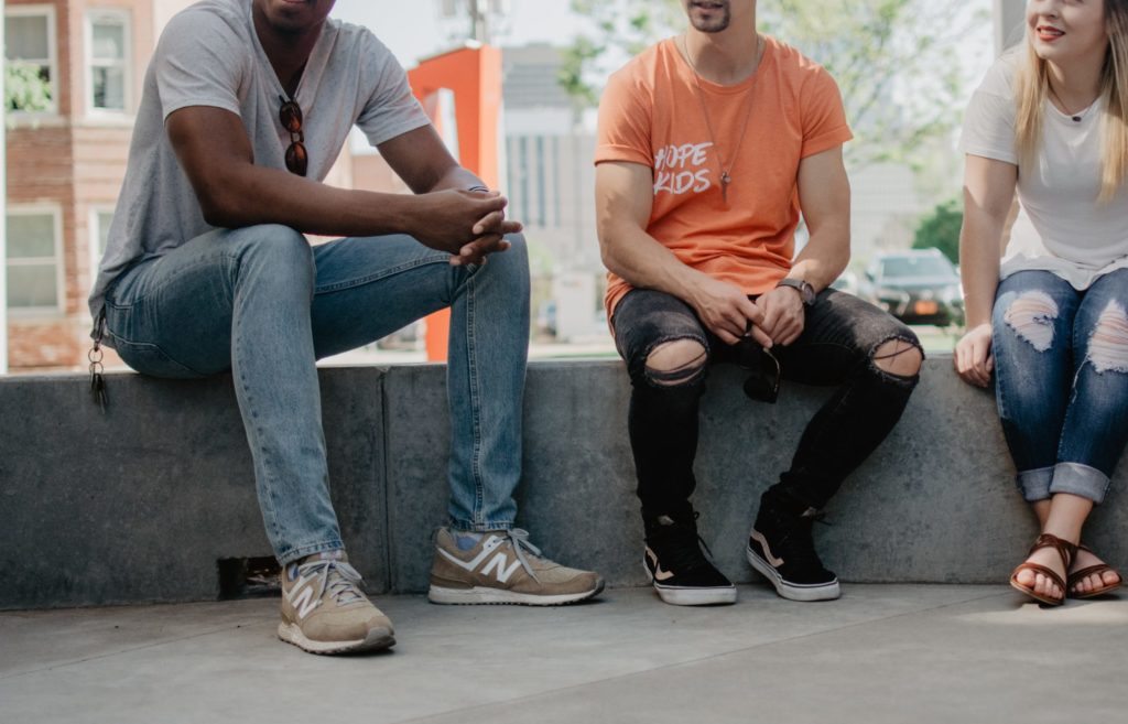 Three people sitting together outside, engaged in conversation